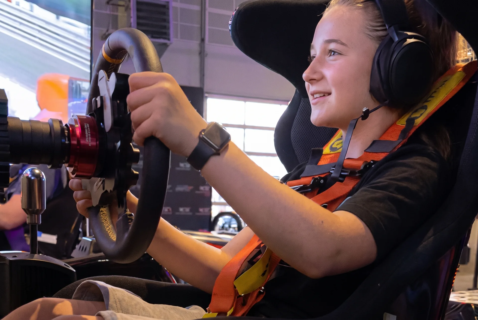 Mädchen mit Headset beim Kindergeburtstag im Rennsimulator (Gesichter mit KI verfremdet)